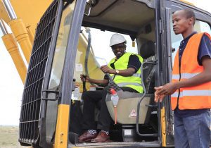 The VC and CEO of KCA University in an excavator at KCA University Kitengela Land Ground Breaking Ceremony