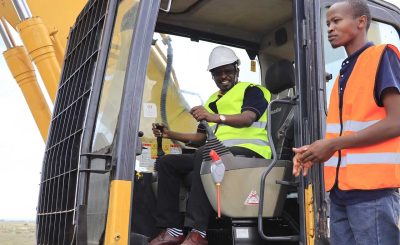 The VC and CEO of KCA University in an excavator at KCA University Kitengela Land Ground Breaking Ceremony